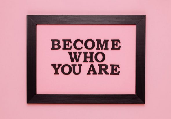 Inspiring quote 'Become Who You Are' framed on a vibrant pink wall, perfect for encouragement.