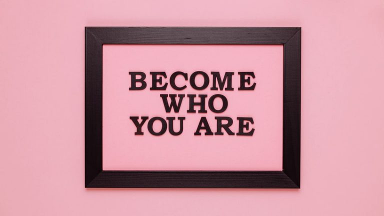 Inspiring quote 'Become Who You Are' framed on a vibrant pink wall, perfect for encouragement.